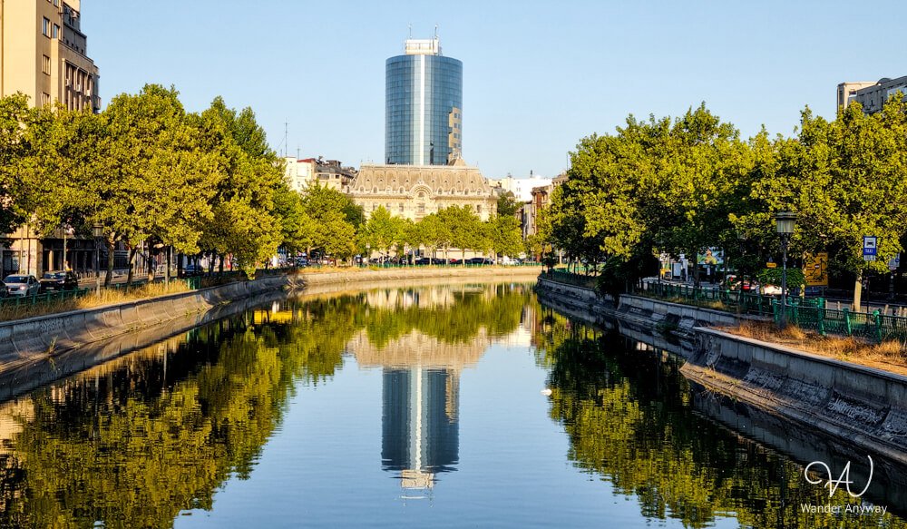 Dâmbovița River flowing through central Bucharest with modern buildings in the background.