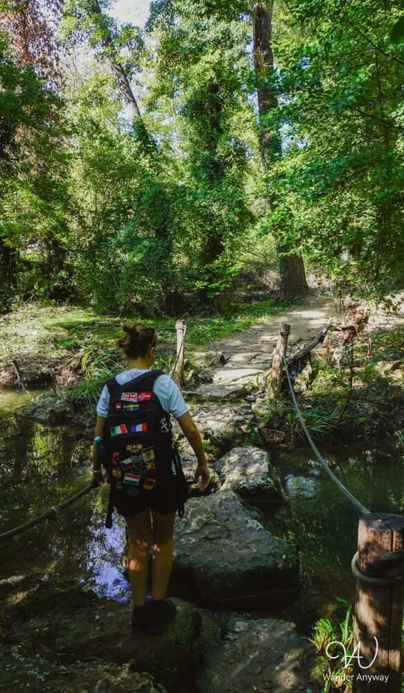 Hiker crossing stone steps over the Elsa River on the Elsa Trail Tuscany near Colle di Val d’Elsa.