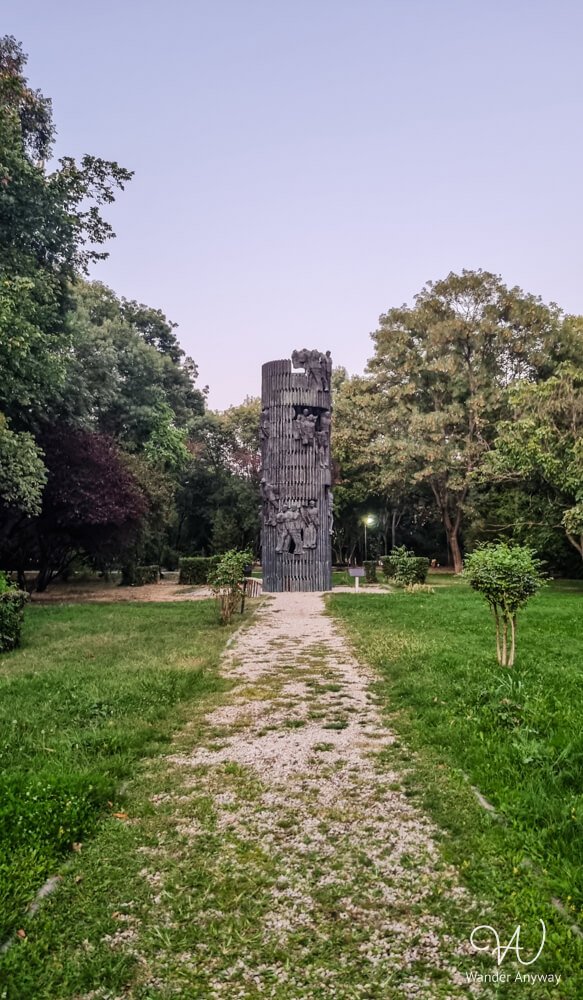 Historic monument and green pathway inside Kiseleff Park in Bucharest.