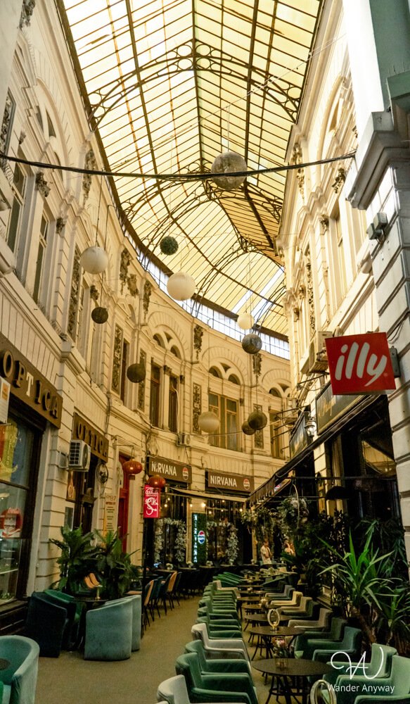 Cafés under the yellow-glass roof of Macca-Vilacrosse Passage in Bucharest Old Town.