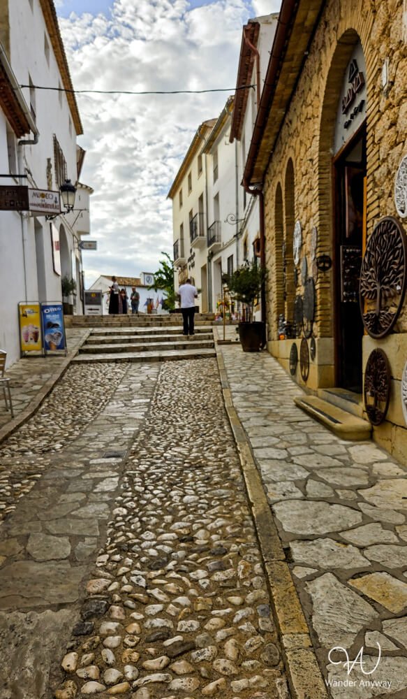 Cobbled historic street in Guadalest lined with old stone houses.