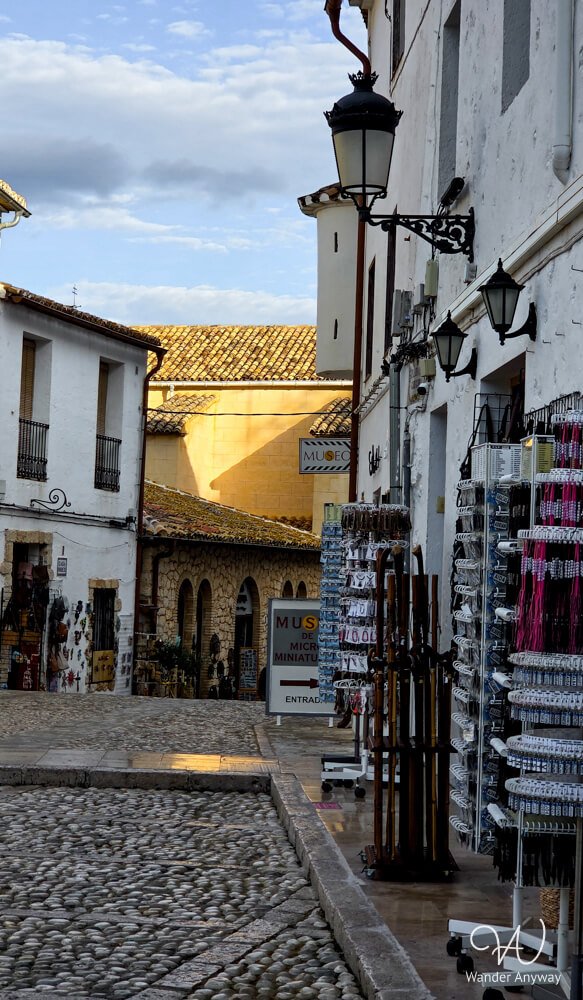 Narrow cobblestone street in Guadalest old town with shops.