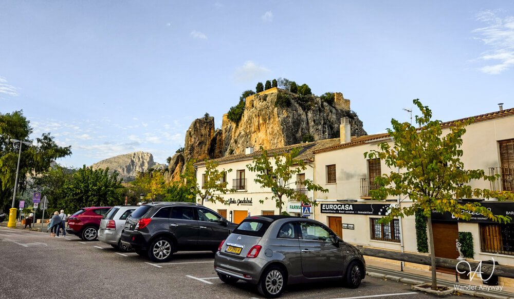 Parking area in Guadalest with cliffs and village buildings in the background.