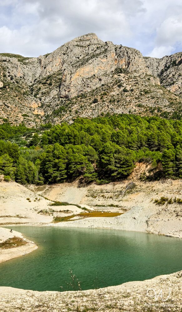 Turquoise reservoir water along the rocky shoreline of Guadalest.