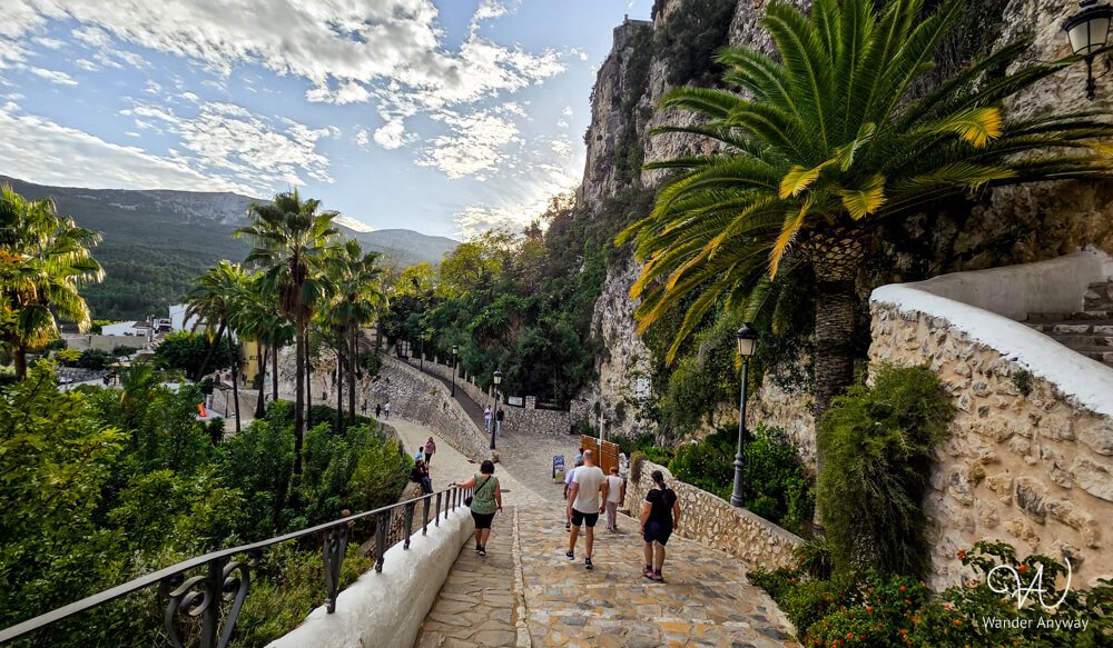 Scenic stone walkway in Guadalest with mountain and palm views.