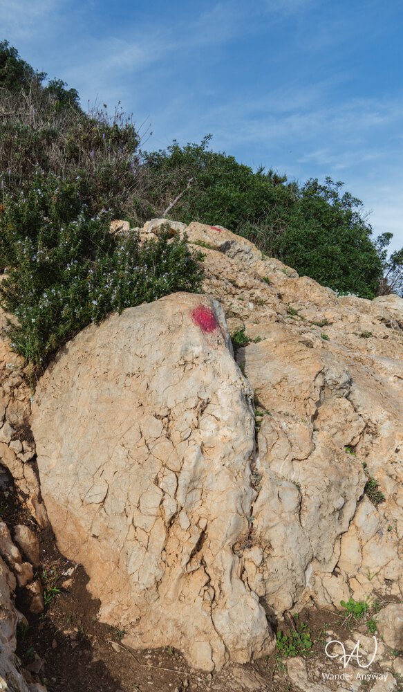 Red dot trail markers on rocks along the Peñón de Ifach hike