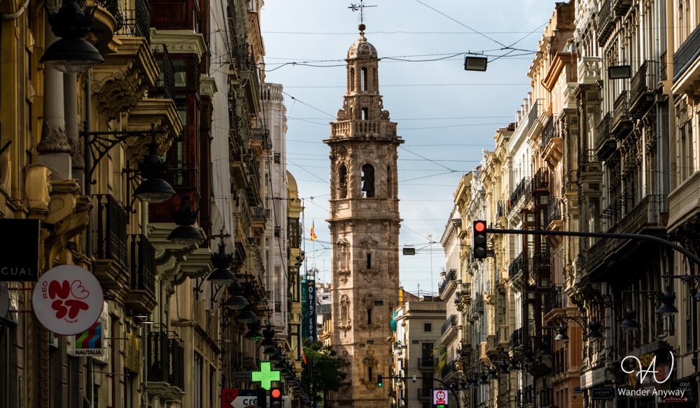 Narrow historic street in Valencia’s Old Town with church tower in the background.
